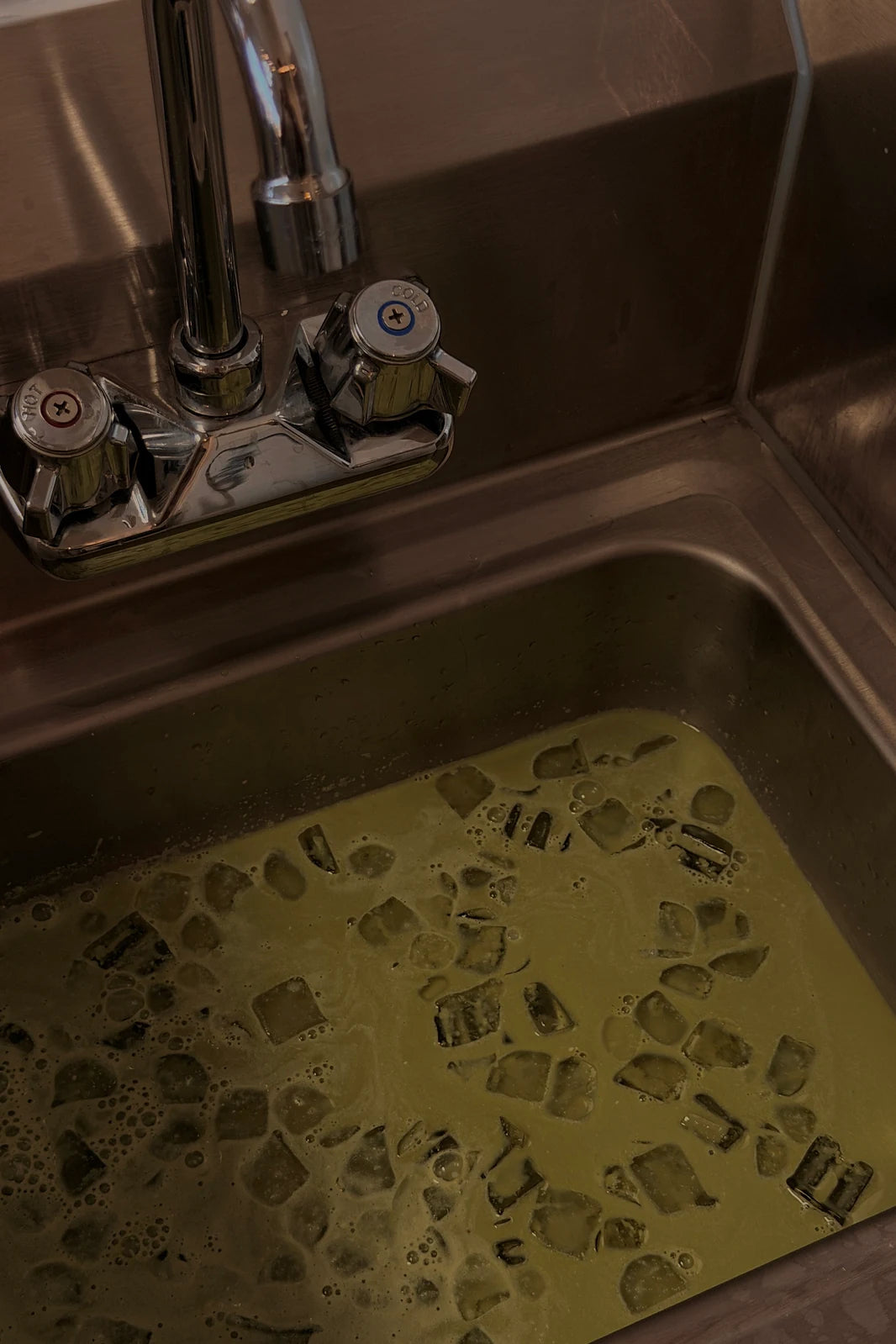 Matcha pooled in a stainless prep sink at the end of service